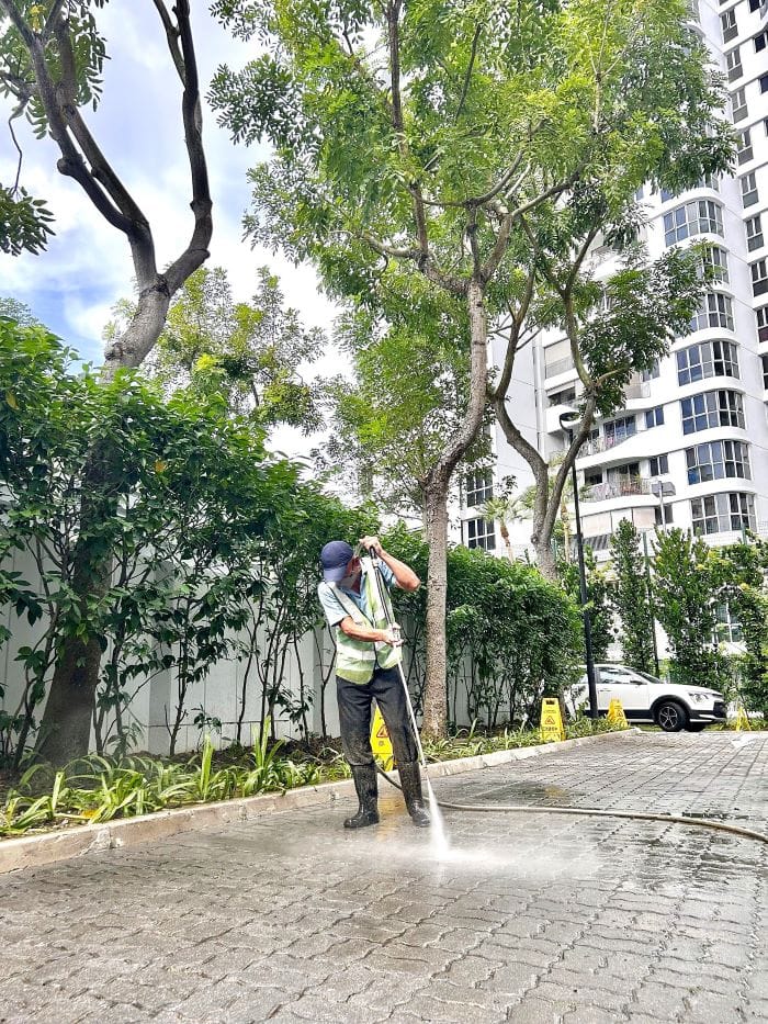 Man wearing cap cleaning the parking compound using water jet